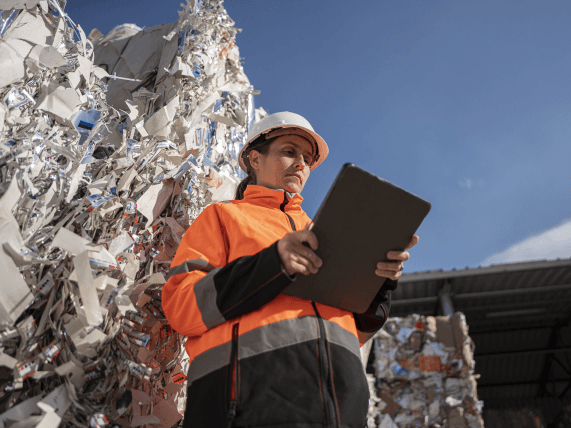 A person with a clipboard standing in front of a dump
