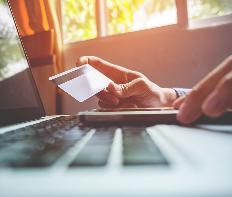Person holding a credit card while making an online payment on a laptop