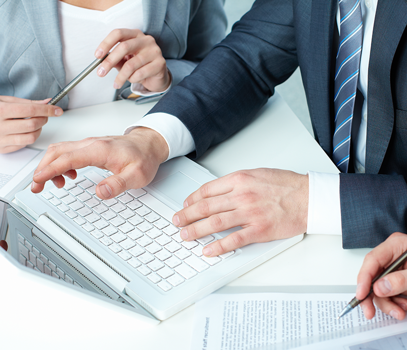 Two colleagues reviewing account documents together at a laptop